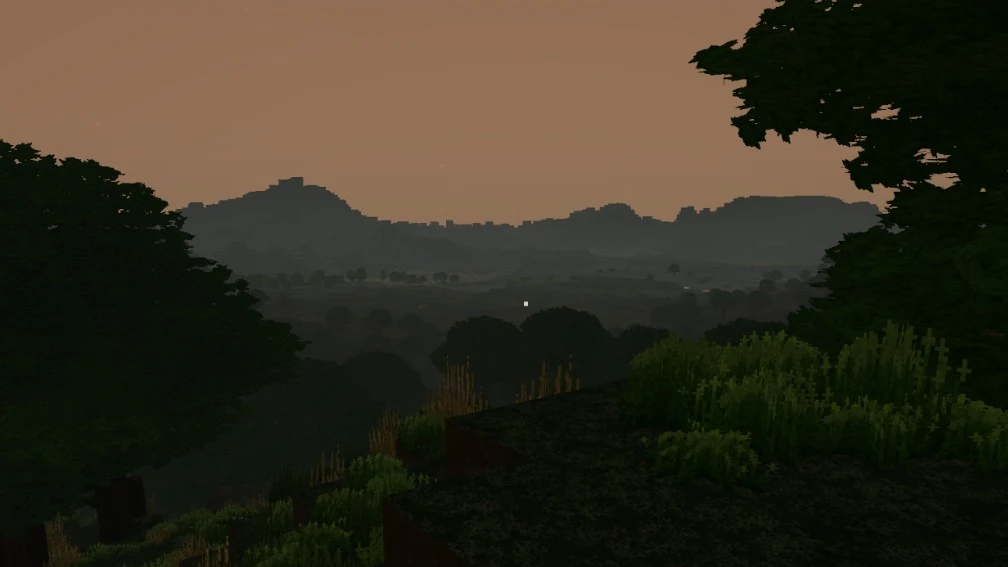 A view from a wooded hillside at dusk, looking across a foggy valley of trees towards distant blocky hills under an orange sky